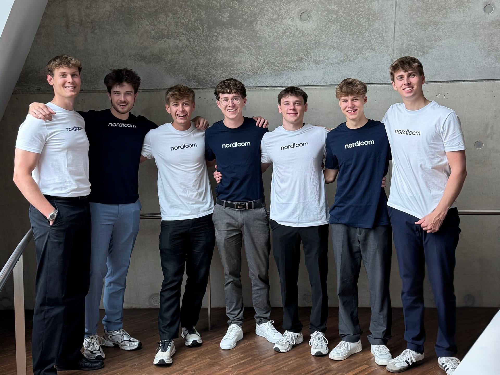 Das Team von Nordloom vor der Betonwand im Büro, Blick in die Kamera